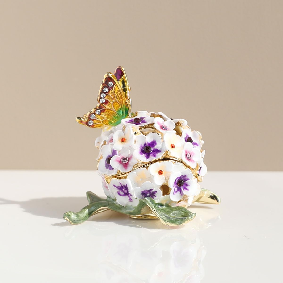 White and purple floral trinket box with butterfly on a light surface