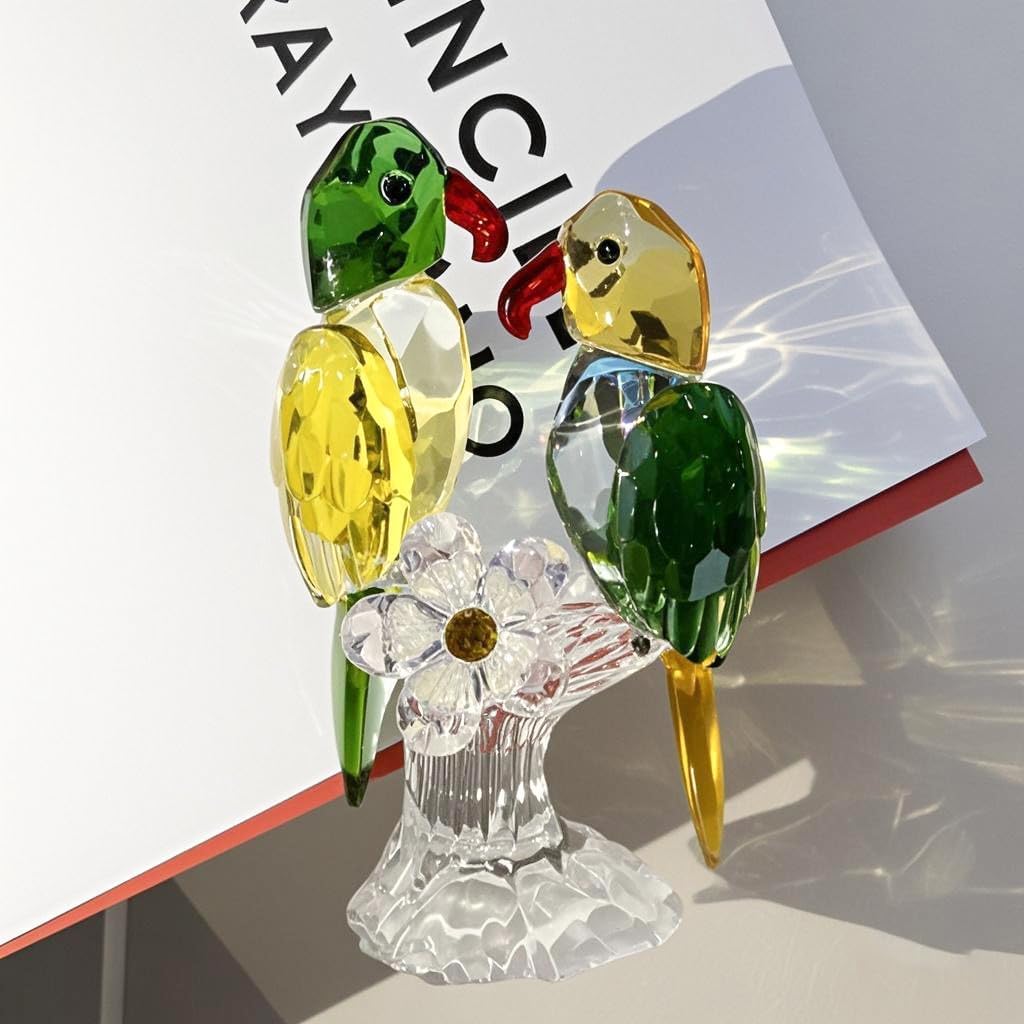 Green and yellow parrot pair on a clear base beside a book