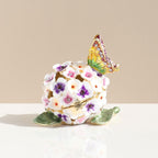 Side view of floral enamel box with gold-toned outlines