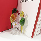 Glass parrot pair displayed beside red and white books