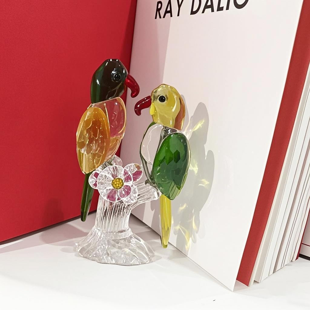 Glass parrot pair displayed beside red and white books