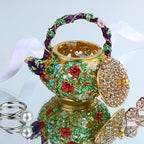 Enamel teapot trinket box with lid open beside jewelry