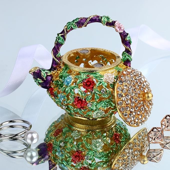 Enamel teapot trinket box with lid open beside jewelry