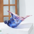 Glass conch shell sculpture displayed on a white block near a window