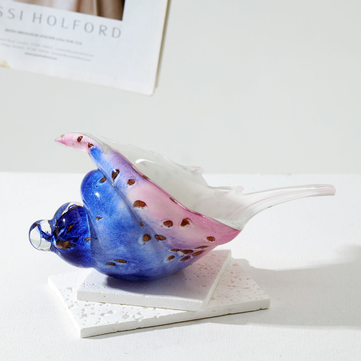 Side view of a blue and pink glass conch shell sculpture