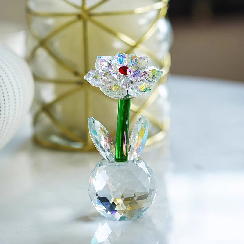 Sunflower glass ornament on a white table beside a vase