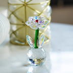 Sunflower glass ornament on a white table beside a vase