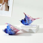 Two colorful glass conch shell sculptures in a tabletop arrangement