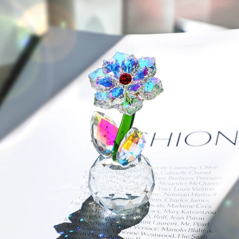 Faceted sunflower glass ornament with green stem on a magazine